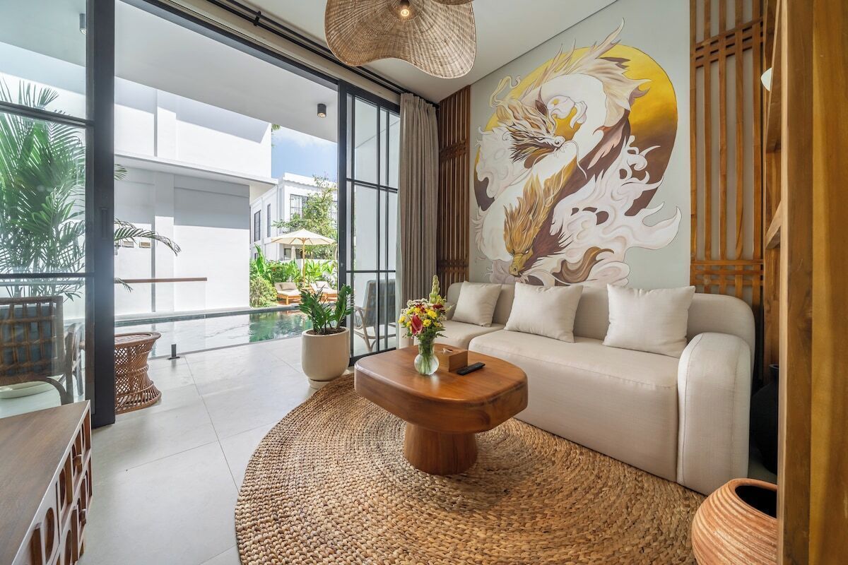 A modern living room with a sofa, a coffee table, and a large mural on the wall.