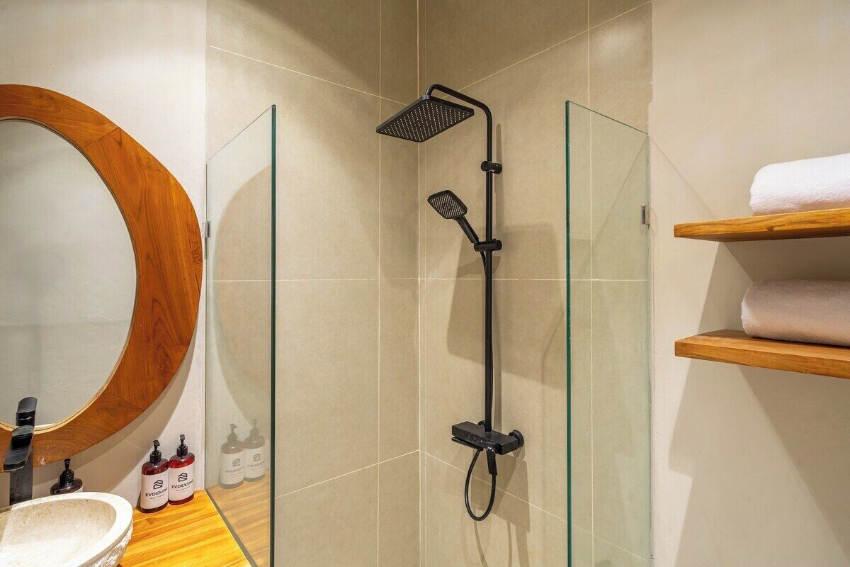 Ein modernes Badezimmer mit einer gläsernen Duschkabine, einem Holzwaschtisch und einem großen Spiegel.