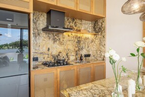 Eine moderne Küche mit Steinrückwand, Holzausstattung und einem Gasherd.
