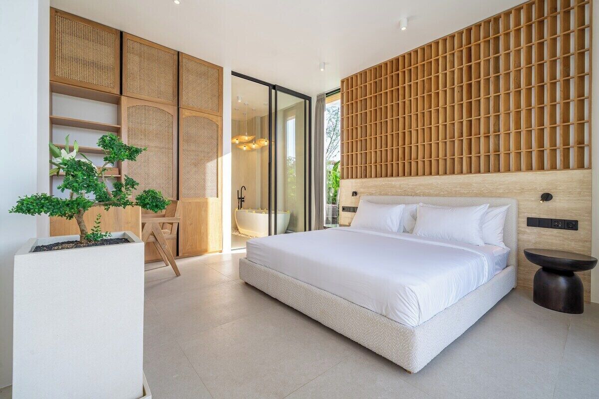 Un dormitorio moderno con una cama grande, una planta en maceta y un panel de pared de madera.
