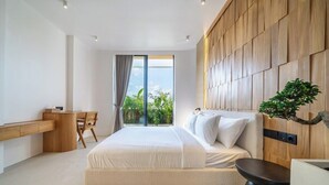 Un dormitorio moderno con una cama grande, un escritorio y vistas al exterior con vegetación.