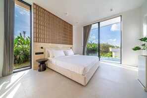 Ein modernes Schlafzimmer mit einem großen Bett, einem Holz-Kopfteil und Blick auf Grün.