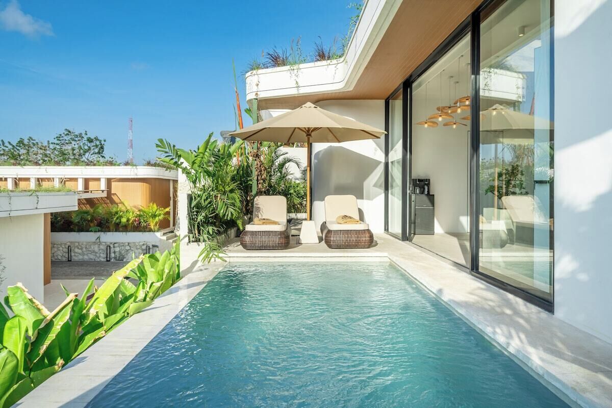 Ein moderner Poolbereich im Freien mit Liegestühlen und einem gläsernen Anbau.