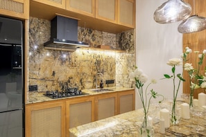 A modern kitchen with a granite countertop, stainless steel appliances, and wooden cabinetry. - Brand New Private 2BR Villa+Huge Pool+Beach Access (South Kuta)