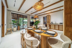 A modern dining area with a wooden table set for four, surrounded by upholstered chairs. - New 3BR Villa Sorento+Top Ubud Location+Huge Pool (Gianyar Regency)