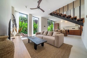 Ein modernes Wohnzimmer mit Sofa, Couchtisch und einer Treppe, die in eine obere Etage führt.