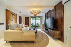 Ein stilvolles Wohnzimmer mit einer Couch, Fernseher und Kunstwerken an der Wand.