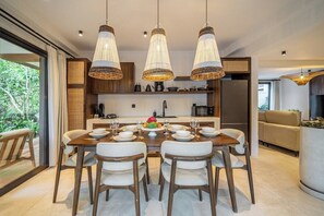 A modern kitchen with a dining area, featuring a large island, pendant lighting, and a view of the outdoors. - Cozy 3BR Villa in Ubud w Garden Bath, Pool & Patio (Gianyar Regency)