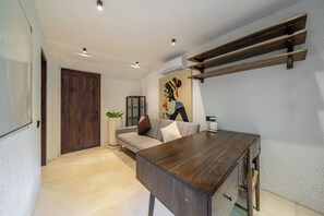Uma sala de estar moderna com uma mesa de centro de madeira escura, um sofá de cor clara e um quadro na parede.
