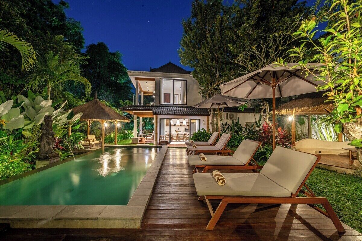 A modern house with a swimming pool, lounge chairs, and umbrellas.