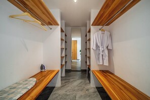 Ein Flur mit hölzernen Bänken, einem aufgehängten Bademantel und einem Spiegel, der einen Raum mit einer Holztür reflektiert.