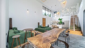 Ein modernes Interieur mit einem Holzesstisch, grünen Sofas und einer Treppe, die in eine obere Ebene führt.