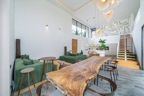 Ein modernes Interieur mit einem Holzesstisch, grünen Sofas und einer Treppe, die in eine obere Ebene führt.