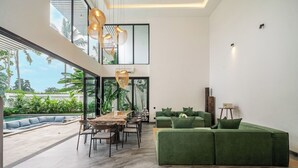 Ein modernes Interieur mit Essbereich, grünem Sofa und Blick ins Freie.