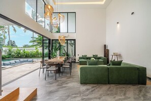 Ein modernes Interieur mit Essbereich, grünem Sofa und Blick ins Freie.