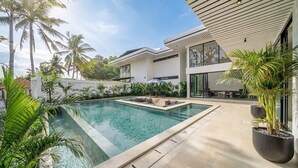 Ein moderner Poolbereich mit klarem Wasser, umgeben von Topfpflanzen und einer Terrasse.