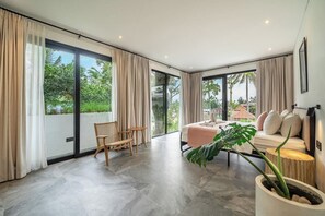 Ein modernes Zimmer mit einer großen Schiebeglaswand, einem Sofa, einem Sessel und einer Topfpflanze.