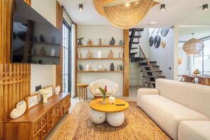 Ein modernes Wohnzimmer mit einer Holztruhe, einem runden Couchtisch, einem Sofa und einer Treppe, die zu einer oberen Ebene führt.