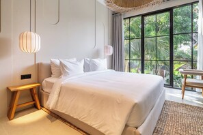 A bedroom with a large bed, a wooden nightstand, a hanging light fixture, and a view of greenery through a window. - Serene 2BR Villa in Ubud w Private Pool & Garden (Tegallalang)