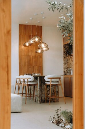 Een moderne keuken met een houten wand, hangende pendelverlichting en een marmeren aanrechtblad.