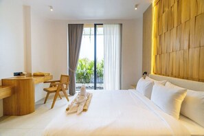 Een hotelkamer met een groot bed, een bureau en een stoel. Er is uitzicht op groen door het raam.