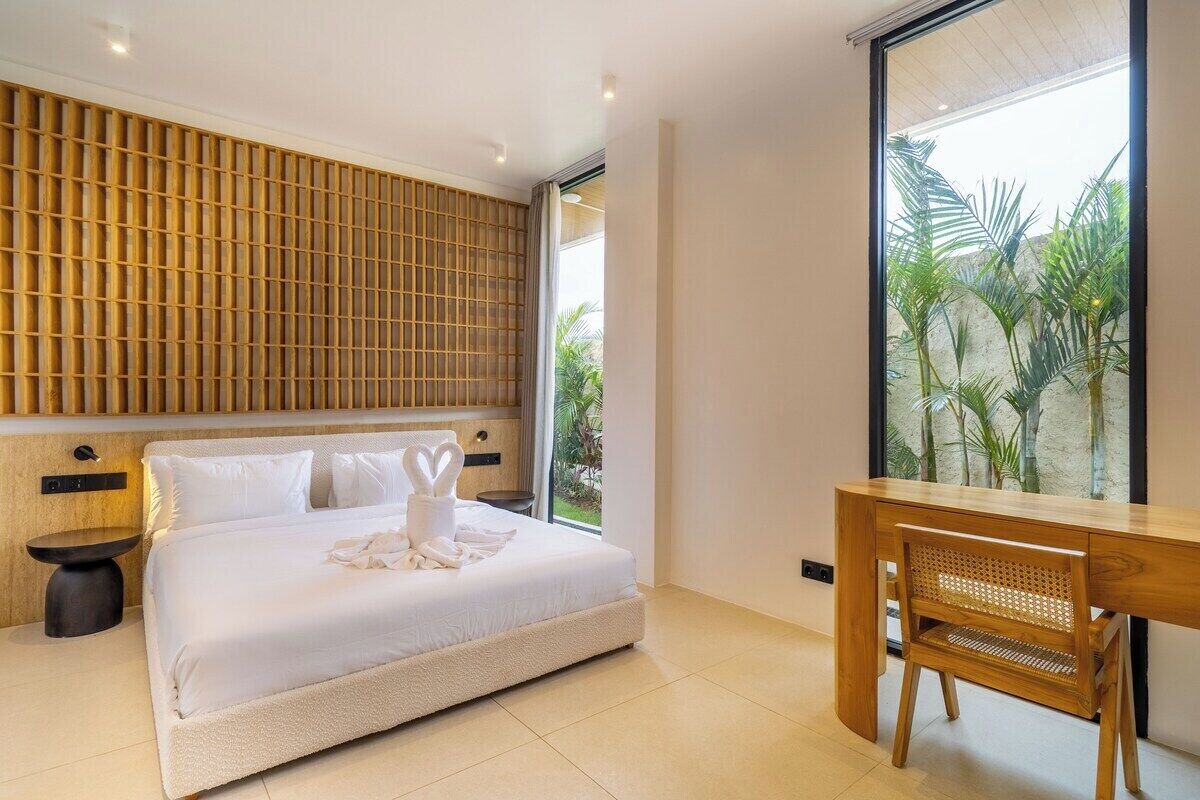 Une chambre moderne avec un grand lit, un bureau en bois et une vue sur la verdure.
