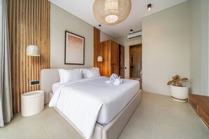 Een moderne hotelkamer met een groot bed, een nachtkastje, een wandlamp en een potplant.