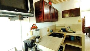 Una cocina con estufa, microondas, licuadora y alacenas.
