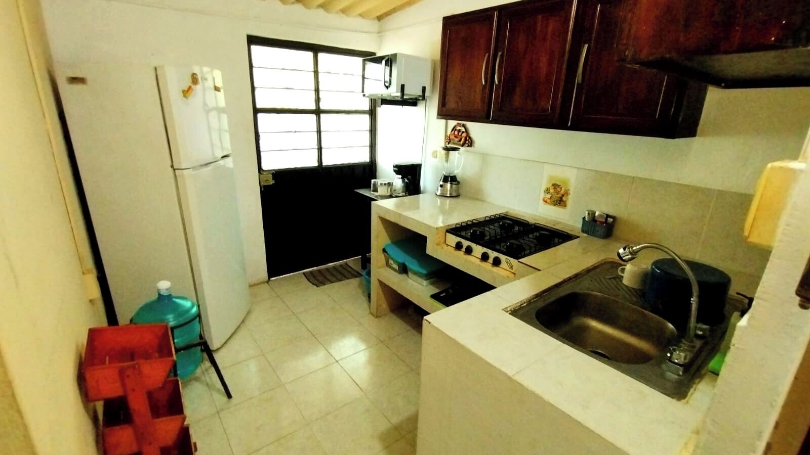Une cuisine de taille réduite, équipée d’un évier, d’une cuisinière et de placards.