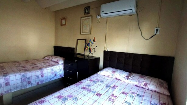 Ein Schlafzimmer mit zwei Betten, einem Schminktisch, einer Klimaanlage und Wandbildern.