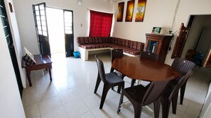 Un coin repas comprenant une table ronde et des chaises, un canapé et un meuble.