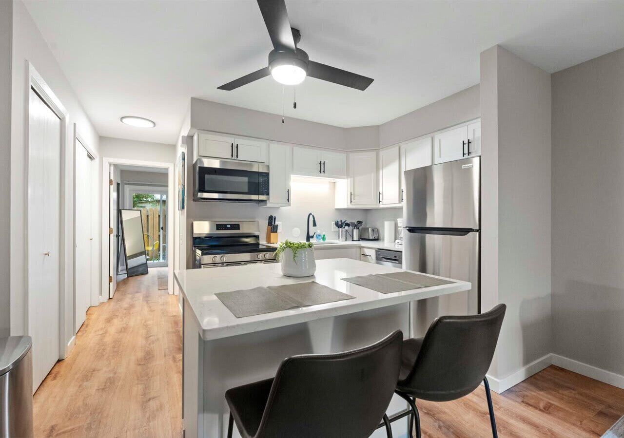 Modern kitchen featuring stainless steel appliances, quartz countertops, and a central island with seating—perfect for cooking, dining, or enjoying your morning coffee.