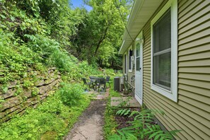 Ein Haus mit einer Terrasse, einer Steinmauer und einem Gartenweg, der zum Haus führt.