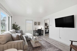 Ein modernes Wohnzimmer mit einer Sofagarnitur, einem Couchtisch und einem flachbildfernseher an der Wand.