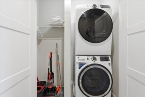 A laundry room with stacked washing machines and a mopping bucket. - Madison Apt with Pool, Gym & Free Parking (Madison)
