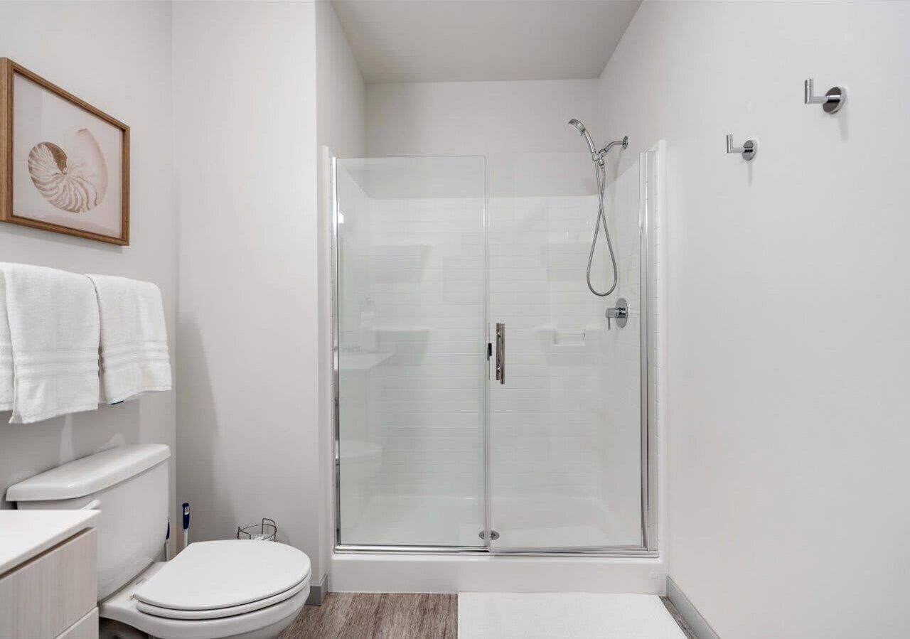 Bright modern bathroom featuring a glass-door walk-in shower, sleek vanity, and soft neutral finishes for a clean, spa-like feel.
