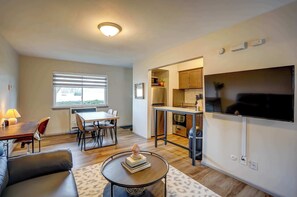 A modern living room with a dining area, a kitchen, and a TV mounted on the wall. - Pet-Friendly Apt Near Med Center + Parking (Milwaukee)