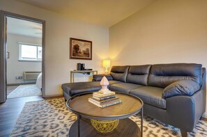 Un salon avec un canapé, une table basse sur laquelle sont posés des livres, une lampe et un tableau accroché au mur.