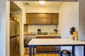 A compact kitchen with stainless steel appliances, a gas stove, a coffee maker, and wooden cabinets. - Pet-Friendly Apt Near Med Center + Parking (Milwaukee)
