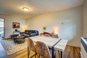 A modern living room with a black leather sofa, a dining table with four chairs, a coffee table, and a painting on the wall. - Pet-Friendly Apt Near Med Center + Parking (Milwaukee)