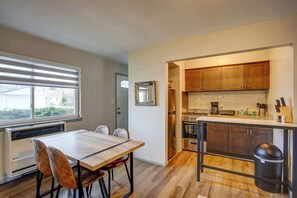 A compact kitchen with a dining area, featuring a built-in oven, a coffee maker, and a trash bin. - Pet-Friendly Apt Near Med Center + Parking (Milwaukee)