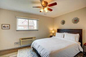 A bedroom with a bed, a ceiling fan, a window, a wall-mounted heater, and a decorative wall piece. - Pet-Friendly Apt Near Med Center + Parking (Milwaukee)