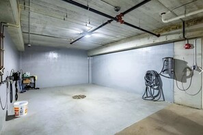 Indoor car-wash bay in the heated garage with hose and drain for year-round vehicle cleaning. - Modern Apt with Pool, Parking & Pet Wash (Madison)