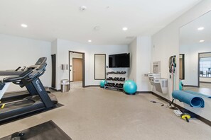 A gym with a treadmill, exercise balls, dumbbells, and a TV. - Near MCW | Free Parking & In-Unit Laundry (Milwaukee)