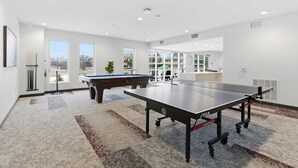 Une pièce spacieuse équipée d’une table de billard, d’une table de ping-pong et d’une table de jeu de flipper.