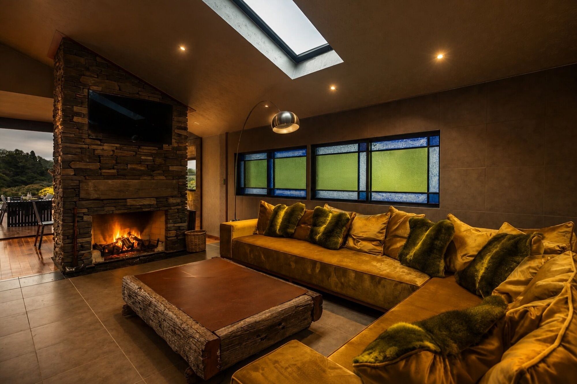 A cozy living room with a stone fireplace, a sofa with cushions, a coffee table, and a skylight.