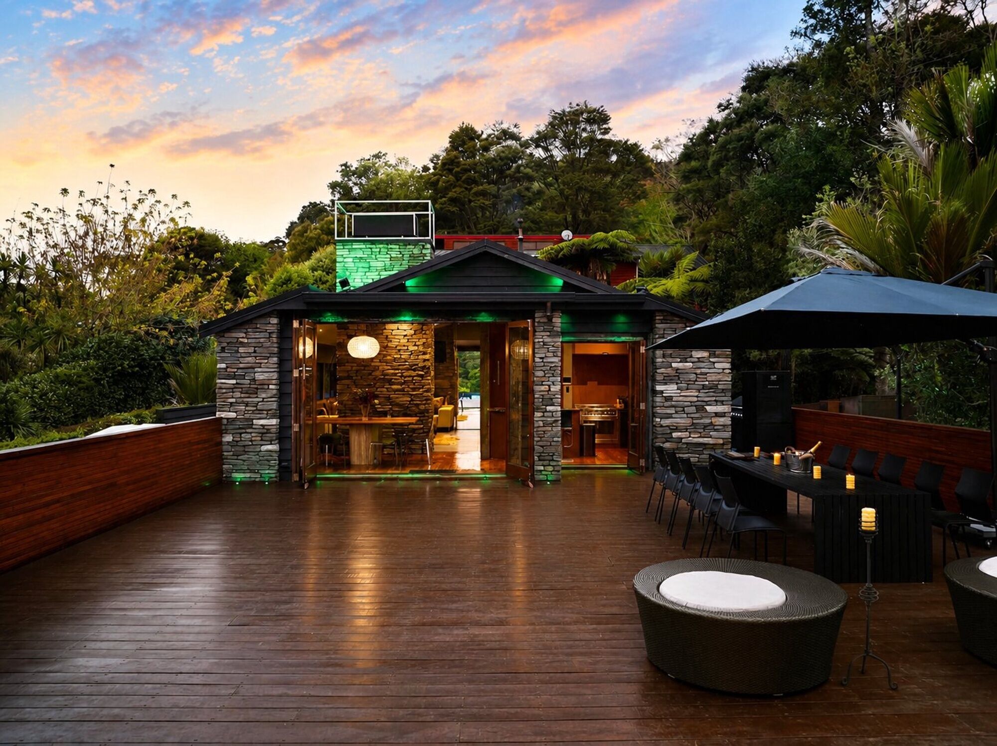 A wooden deck with outdoor seating and a stone building with a glass entrance.