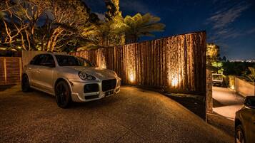 A white car parked in front of a wooden fence with a starry night sky in the background.