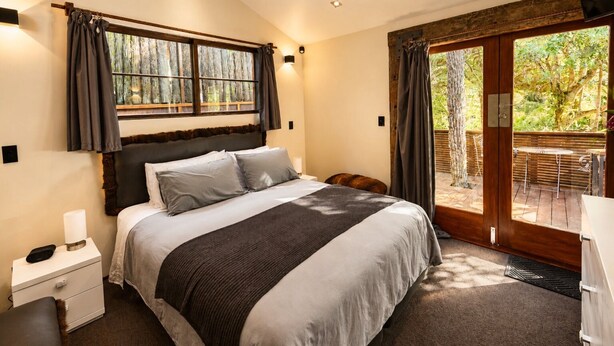 Ein Schlafzimmer mit einem großen Bett, einem Nachttisch und Blick ins Freie durch eine Schiebetür.