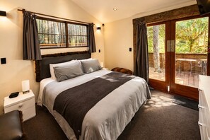 Ein Schlafzimmer mit einem großen Bett, einem Nachttisch und Blick ins Freie durch eine Schiebetür.